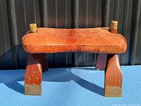 Front view of leather-topped saddle footstool