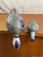 Top view of both pottery ducks hanging over shelf edge