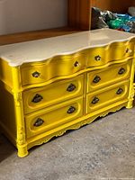Front view of yellow painted dresser with marble top and six drawers