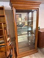 Full view of oak display cabinet with glass door and shelves