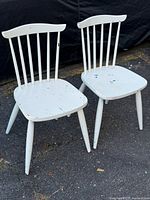 pair of white painted spindle-back chairs on pavement