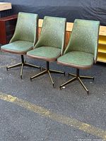 three green floral swivel chairs side by side