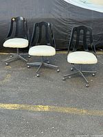 Three lucite and chrome swivel chairs on pavement