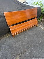 Front view of walnut headboard and footboard leaning against surface