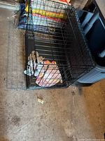 Overall view of folded black wire dog crate showing size and tray