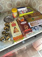 Lot overview showing incense boxes, camphor jar, matchboxes tray, metal holder and brass bells