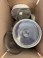 Top-down view showing nested round casseroles, rectangular casserole with lid, glass lids visible