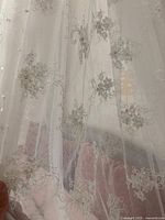 Close-up of sheer curtain fabric showing floral lace embroidery