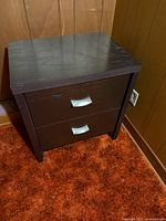 Full view of dark brown two-drawer nightstand showing handles and overall condition