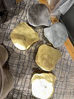 Five gold and silver plaques arranged face up showing finishes