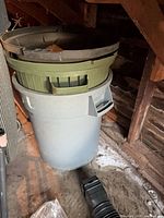 Gray trash can with green bin inside and two black trays on top