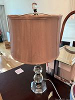 Full view of one lamp showing crystal body, shade, finial, cord and plug
