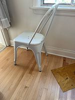 3/4 view of white metal high-back chair near window