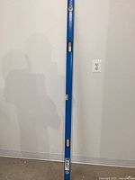 Full view of the 6-foot blue Empire level leaned against wall