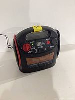 Front view of jump starter showing brand label, controls, digital display and clamps