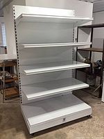 Full view of white steel gondola shelving unit on casters