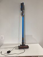 Full view of assembled Levoit LVAC-120 cordless stick vacuum standing upright with charger on table