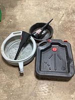 Three oil drain pans and two funnels on floor