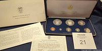 Open presentation case showing eight proof coins, outer sleeve, certificate, pamphlet