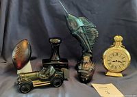 Group view of five Avon figural bottles: football, stamp handle, marlin, car, pocket watch