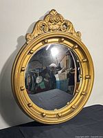 Front view of gilt convex mirror showing entire frame and mirror surface