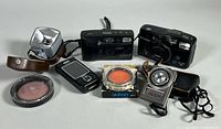 Group shot showing both cameras, light meter, accessory, two filters and flip phone
