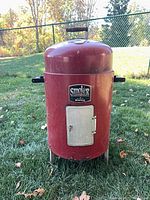 Full view of red Char-Broil bullet smoker showing body, door and legs