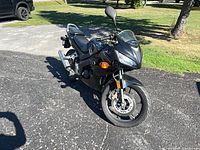 Front three-quarter view of black Honda CBR125R on driveway
