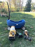 Wider shot showing wagon and three toy vehicles on grass