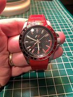 Front view showing dial, bezel, hands, and red leather strap