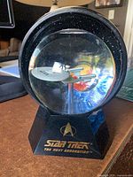 Front view of globe showing Enterprise model and lit starfield, Star Trek logo on base