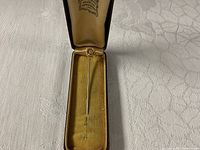 Stick pin in brown case, lid partially open