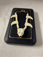 Full necklace on display case showing gold chain and bone polar bear carvings