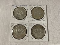 Front view of four Canadian silver dollars in holders showing dates and varieties