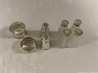 Full lot view showing two sterling napkin rings, two sterling shakers, four glass shakers