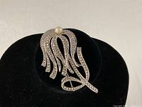 Front view of sterling silver brooch on display stand showing marcasite and pearl