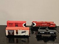 Four HO scale train pieces: CP Rail locomotive, CP Rail boxcar, Tootsie Roll boxcar, CN tank car