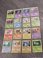 All twenty Pokémon cards laid out in five rows of four on wood floor