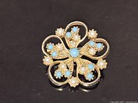 Front view showing overall floral design, cabochons, pearls, and gold-tone finish