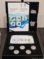 Open presentation box showing coins, stamps and emblem pieces