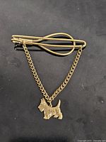 Full view of gold tone tie clip with attached chain and Scottie dog charm