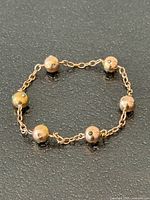 Full view of bracelet showing six gold spheres with turquoise insets and chain links