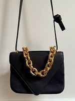 Front view of black leather envelope bag with gold chain and strap