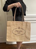Full view of tote bag being carried showing size, handles, and exterior logo