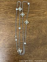 Full view of entire 36-inch necklace laid flat showing chain, quatrefoil stations, pearls and clasp