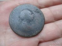 Obverse side of worn copper coin on palm