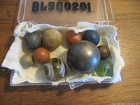 Open plastic case holding assorted metal, wooden and glass balls