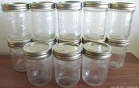 Front view of stacked clear fruit-embossed glass jars with metal lids