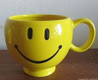 Front view showing smiley face graphic, pedestal base and handle