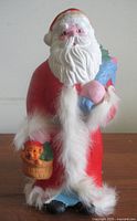 Front view of painted ceramic Santa with toy sack and basket